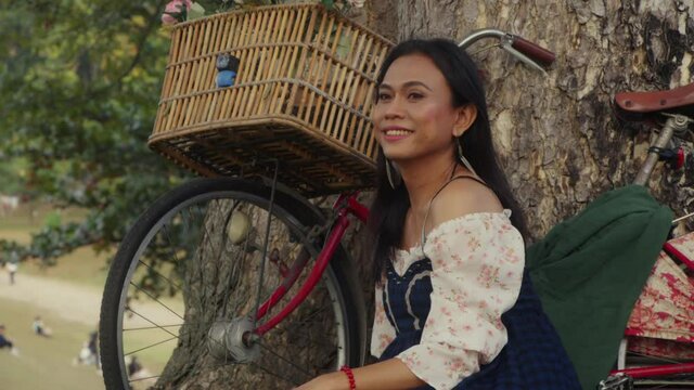 Transgender Asian woman standing with her bike and looking at the camera.