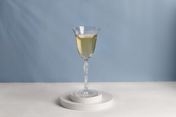 Wine in glass on white podiums. Glass of wine on pedestal in sunlight. Shadow on blue wall.