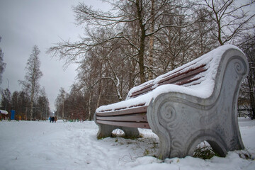 Snow is lying on a bench in the park