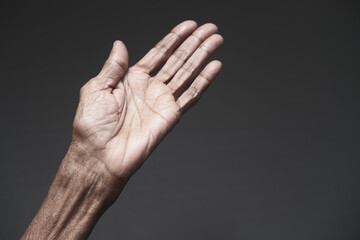 close up of hands of a elderly person against gray background 