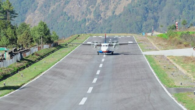 Plane rolling down over runway at mountain small town after landing to airfield