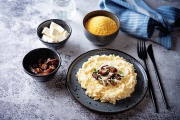 Corn porridge with fried bacon, parsley and Feta cheese in a bowl
