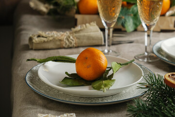 Table setting with Christmas decoration. Festive Christmas dinner, food background. Wine glasses and fresh tangerine on plate.