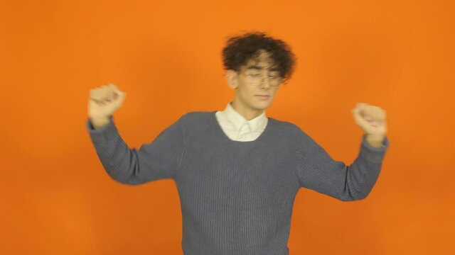 Funny guy posing in the studio. Orange background.