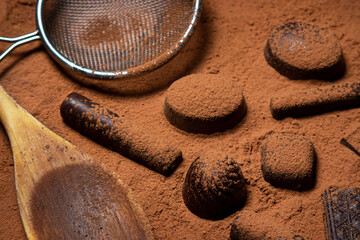 Chocolates lie on cocoa powder. Chocolate making concept. Chocolate sprinkled with cocoa. Cinnamon...