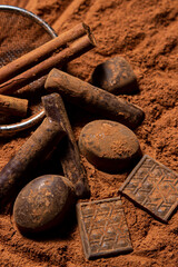 Chocolates lie on cocoa powder. Chocolate making concept. Chocolate sprinkled with cocoa. Cinnamon...