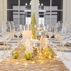 Beautiful table setting with Christmas decorations. Gold colors. Interior of the room