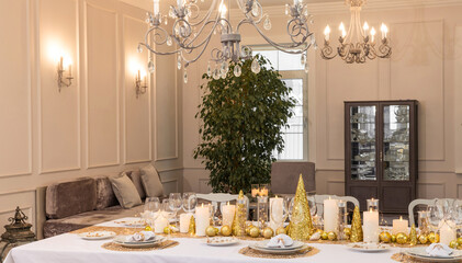 Beautiful table setting with Christmas decorations. Gold colors. Interior of the room