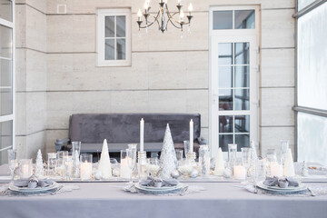 Beautiful table setting with Christmas decorations. Silver colors. Interior of the room