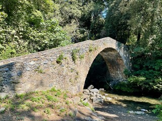 Fototapeta na wymiar Old Roman stone bridge over Bucatoggio river in Moriani, Corsica, France.