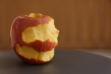 Bitten red apple on the dark gray floor. Fuji apple.
