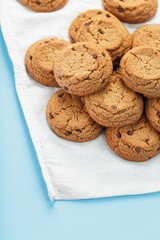 A bunch of oatmeal cookies with chocolate on a napkin on a blue background