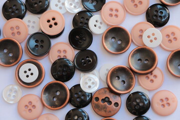 Black, white and salmon colors clothing buttons. Buttons scattered on the floor. Four hole buttons