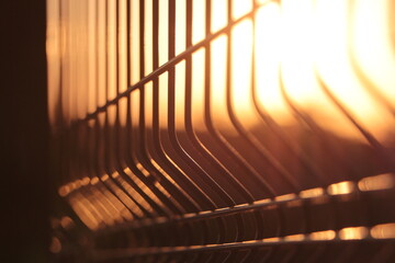 Sunlight shining behind metal fences. Sunset. Golden hours. Balustrade, Rail.