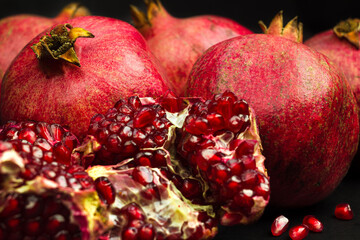 Garnet fruits and pulp on black background. Fresh pomegranate fruits and seeds close up. Healthy...