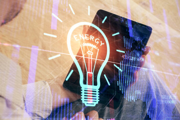 Double exposure of man's hands holding and using a digital device and bulb hologram drawing. Idea concept.