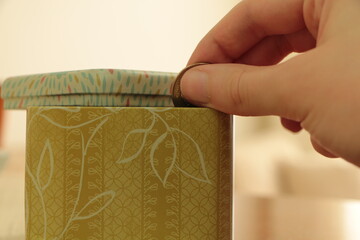 Hand throwing money into green patterned box. Be thrifty. Save money.