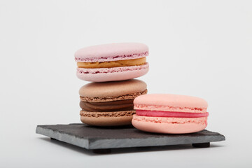 Colorful macaroons on grey mat on white background. Sweet bakery, copy space.