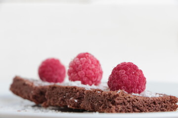 Raspberry and coconut zest on three pieces of chocolate cake.  Brownie	