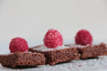 Raspberry and coconut zest on three pieces of chocolate cake.  Brownie	