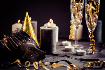 Party still life with carnival mask, candles on black background