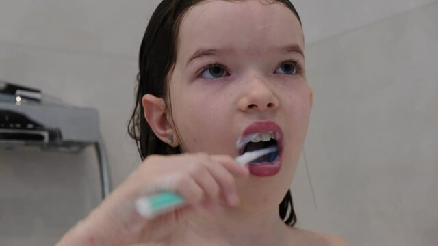 little girl brushing her teeth in the bathroom
