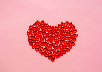 Valentine's day concept. Heart of beads in the shape of a heart of red on a pink background.
