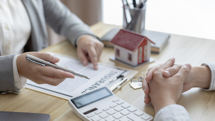 Real estate agent or sales manager talks to clients about the terms of buying a home and collateral...