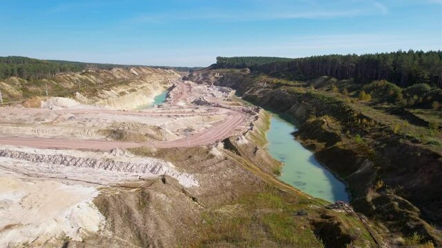 Artificial lake in a chalk quarry. Amazing industrial landscape. Drone view of opencast mine. Turquoise background of the water in open pit. Technogenic mountains formed during chalk mining. 
