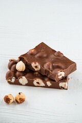 Delicious milk chocolate bars with nuts close up. Stack of chocolate slices Hazelnut pieces tower. Sweet food photo concept