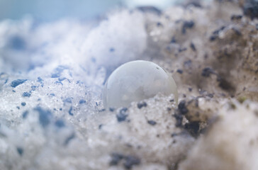 The glass ball lies on a dirty snowdrift nearby.