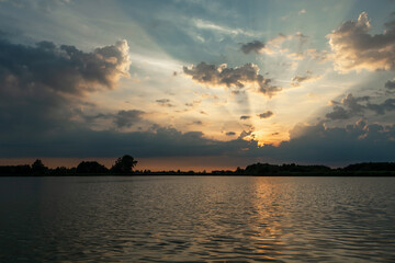 Sunset behind the clouds over the lake, Stankow, Poland