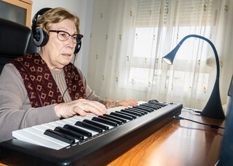 Caucasian elderly woman learning music and playing the musical keyboard.