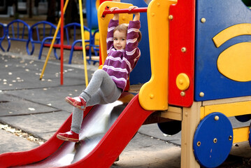 The child slides down the slide in the playground. Children's active games.