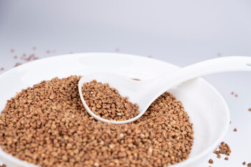 A bowl of buckwheat with a white spoon. Good food. Cereal culture