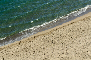 Top view on the sandy beach and turquoise mediterranean sea, beautiful waves and footprints on the sand