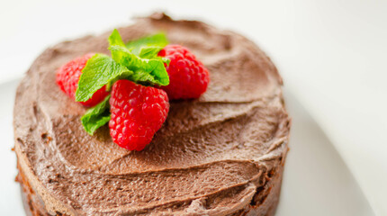 Gluten free tasty round cake based on Belgian chocolate decorated with fresh raspberries and mint