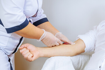 The nurse takes a blood sample, inserting a needle into a man's vein.
