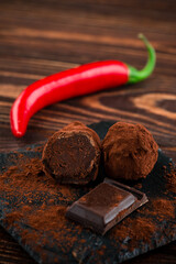 Pieces of Chocolate with Red Chilli Pepper on wooden background closeup. Broken dark chocolate