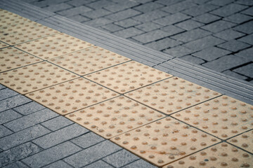 Yellow Braille blocks on public transport station for person with a physical disability