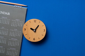 Fototapeta na wymiar close up of calendar and clock on the blue table background, planning for business meeting or travel planning concept