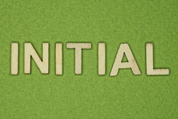 gray word initial from small wooden letters on a green table
