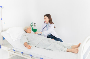 Asian doctor talk with old female patient about disease symptom, doctor use stethoscope listening lung of patient, elderly health check up, happiness hospital