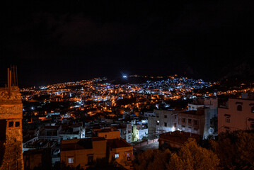 High angle view of lit residential buildings in Chefchaouen old town under the dark night sky