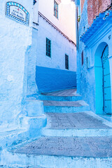 Naklejka premium Chefchaouen, Morocco. October 10, 2021. Traditional residential buildings along narrow street painted in blue and white color