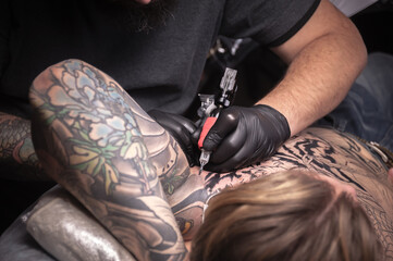 Professional tattooer at work in tattoo parlour