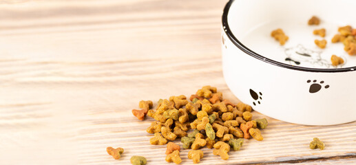 Pet food in a bowl on a wooden vintage background. Dry food for dogs or cats in a bowl on a wooden background