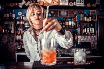 Girl bartender mixes a cocktail in the taproom