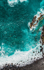 Turquoise waves and sea foam from above. Atlantic ocean coastline with rocks and stones. Madeira island, Portugal. Aerial drone photography. Beautiful landscape. Scenery outdoor background. © svetakhovrina