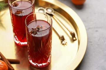 Traditional christmas beverage mulled wine with red cherry juice, orange tangerines, cinnamon sticks and anise on a round golden tray